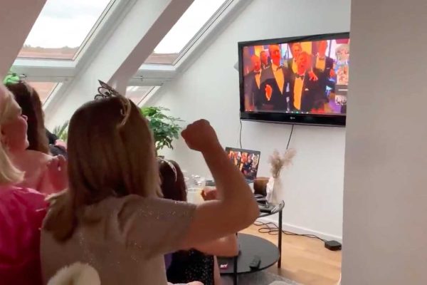 Vardagsrum med tjejer i tiaror och på TV-skärmen sjunger Gosskören live